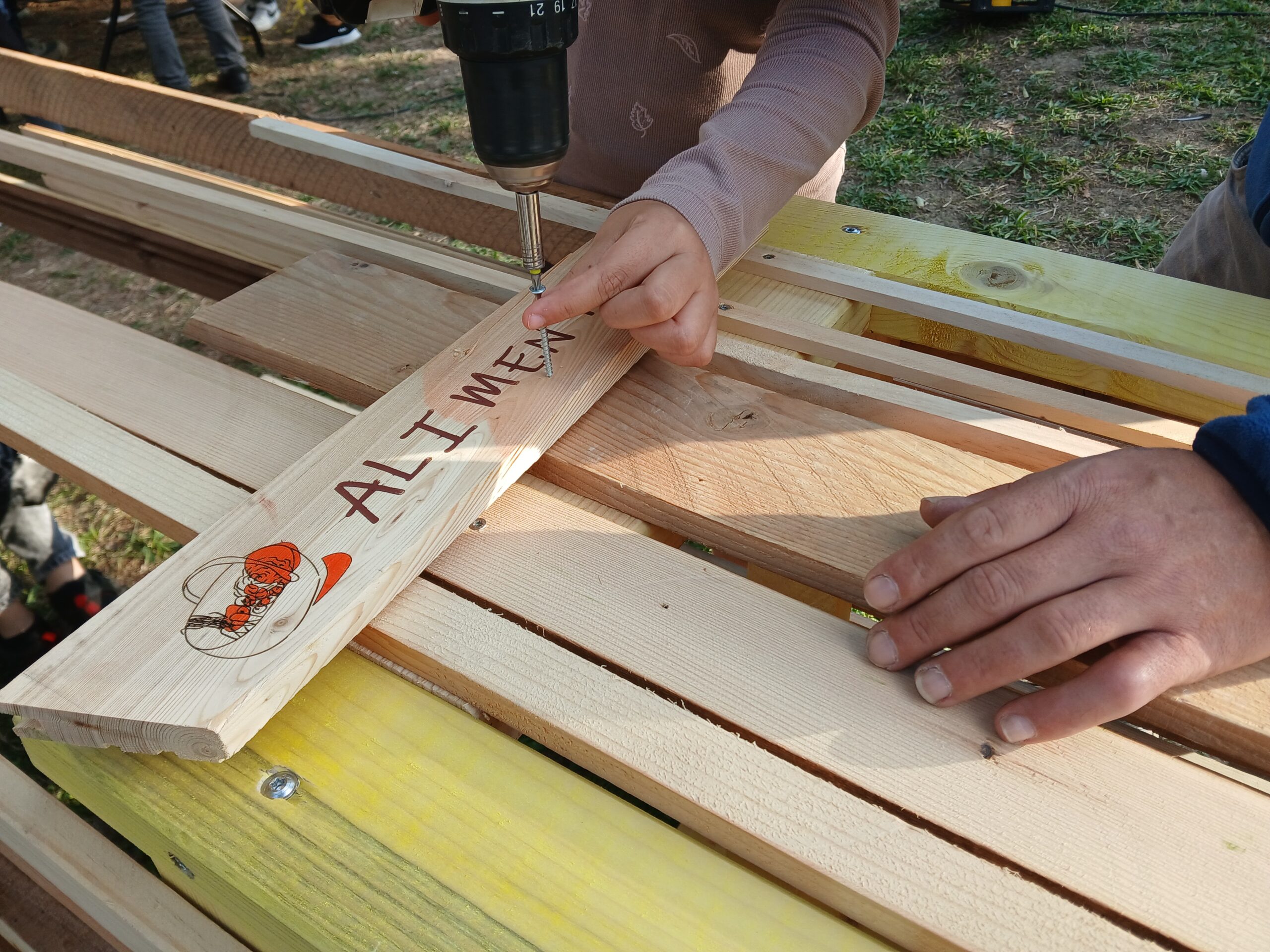 Mains qui utilisent une visseuse pour visser une planche avec écrit le mot Alimentation