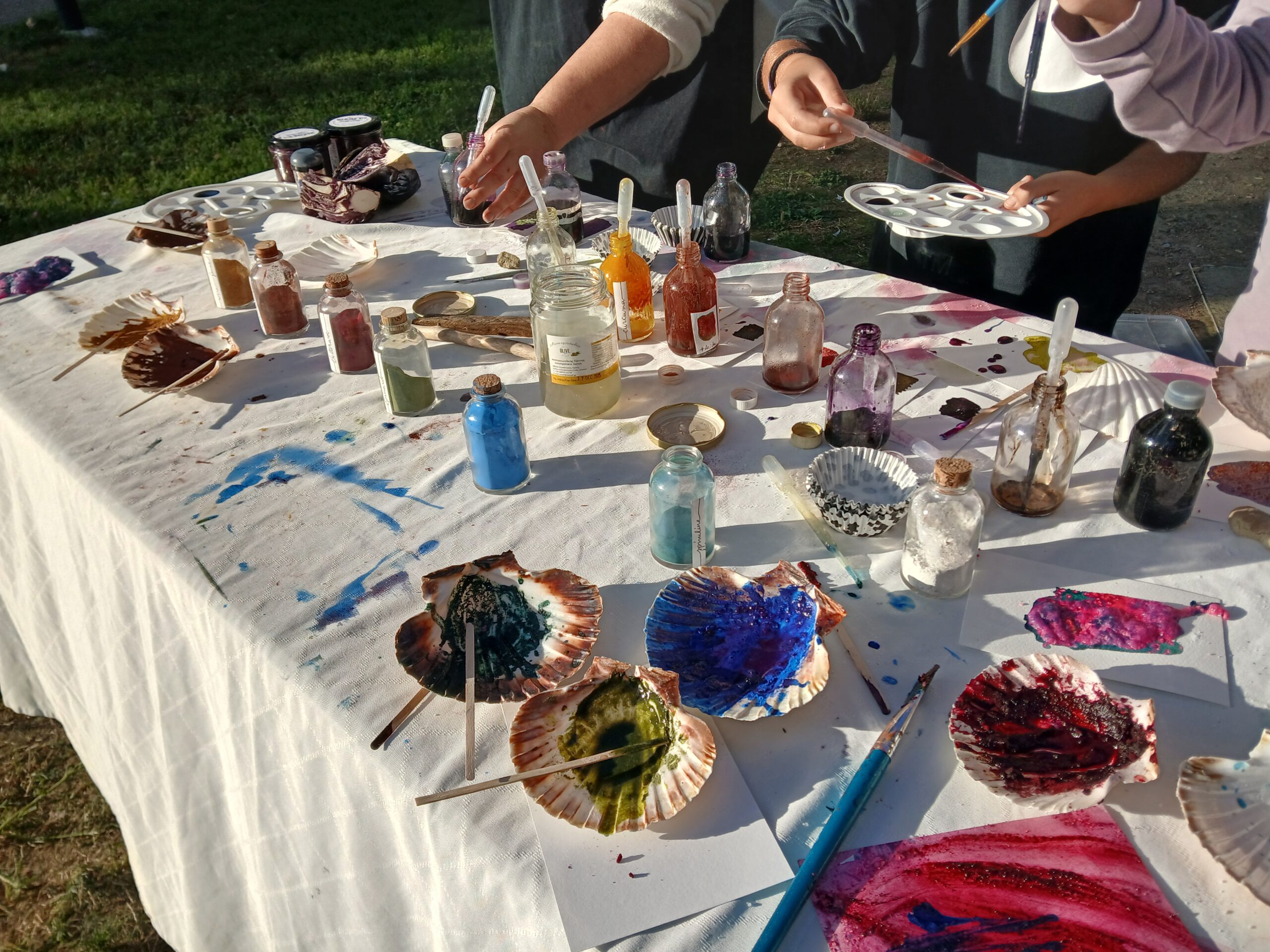 Table avec flacons d’encres et pigments très colorés pour réaliser de la peinture naturelle